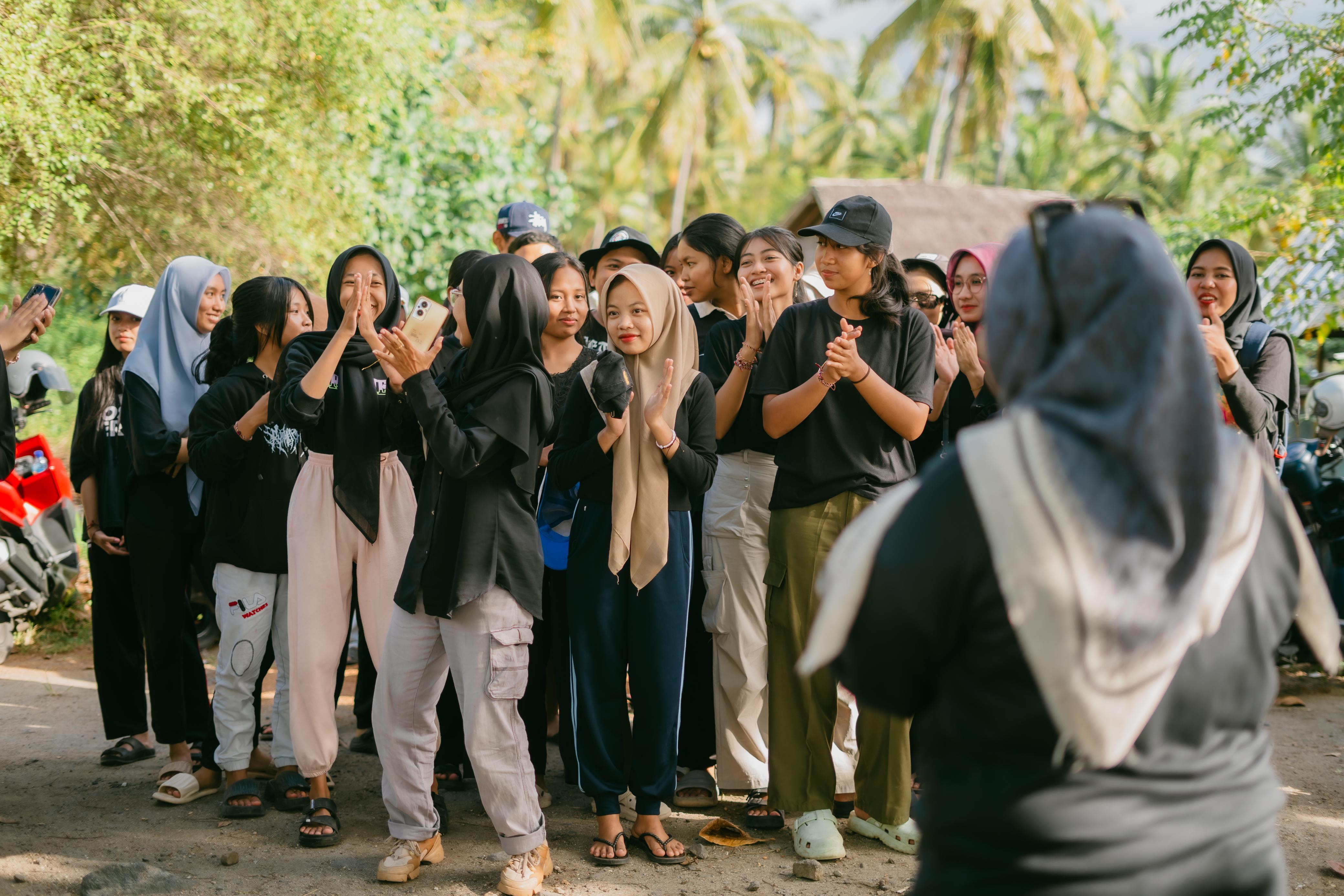 Participants from various institutions gather on Tembobor Beach, preparing to begin the conservation activity. Rows of young mangroves in the background symbolize the natural buffer they provide against coastal degradation.
